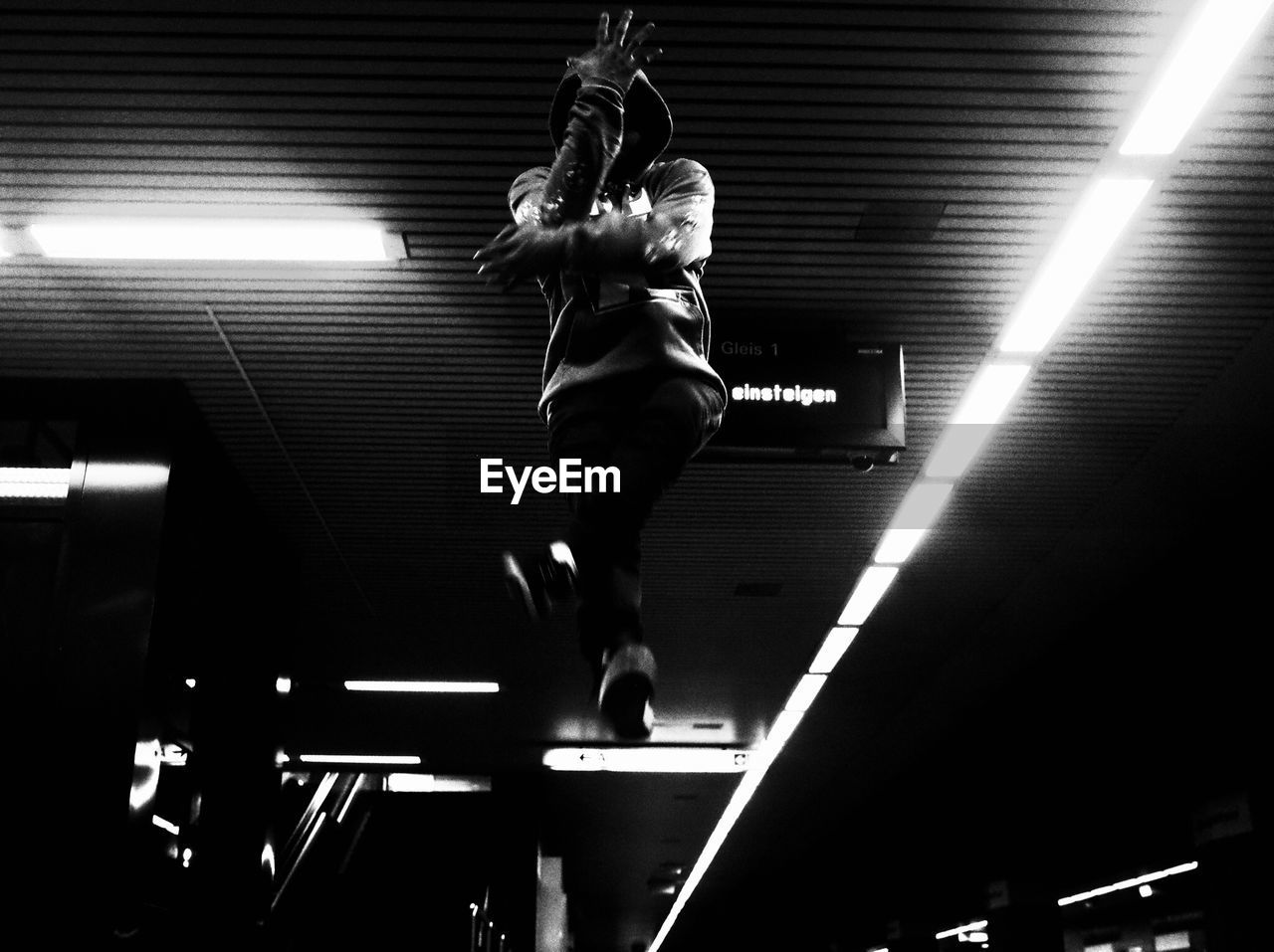 LOW ANGLE VIEW OF MAN WITH ILLUMINATED LIGHTS IN CEILING