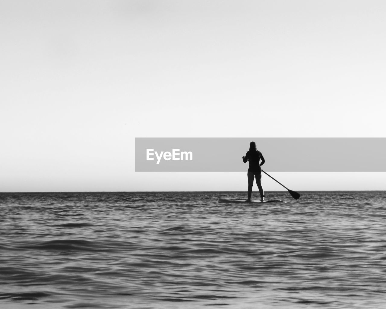 SILHOUETTE OF MAN STANDING IN SEA AGAINST CLEAR SKY