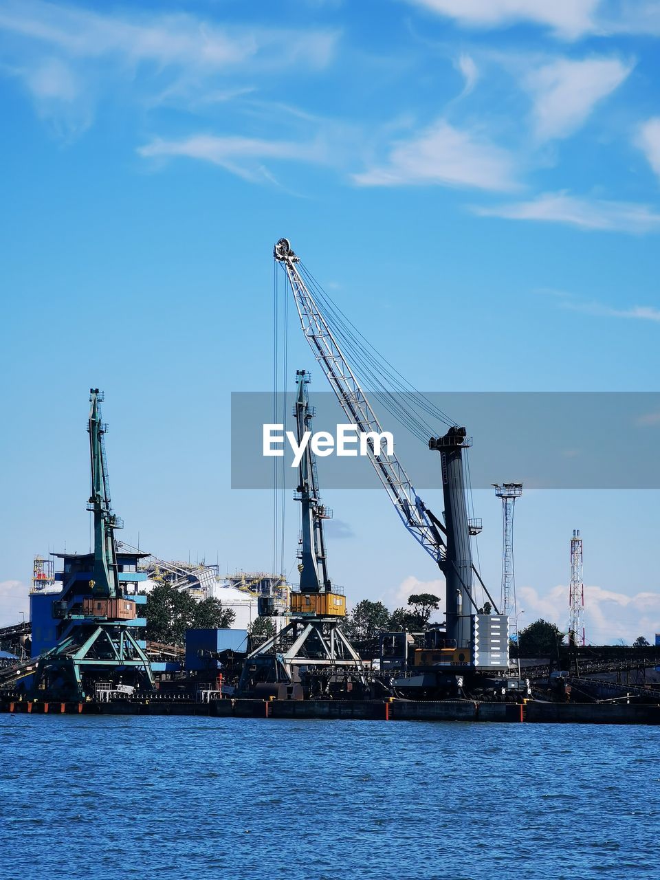 Cranes at commercial dock against sky