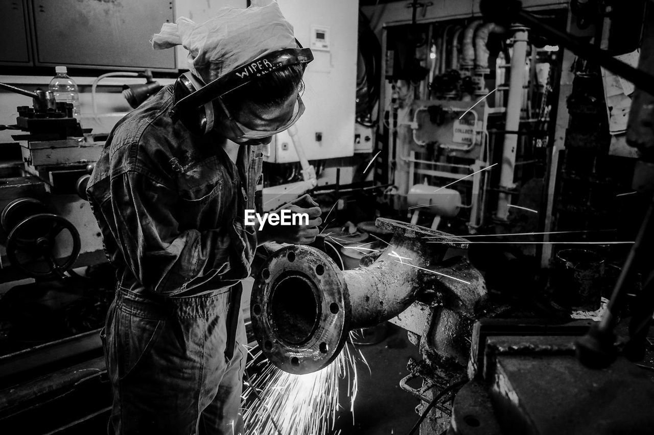 MIDSECTION OF WOMAN WORKING IN MACHINE