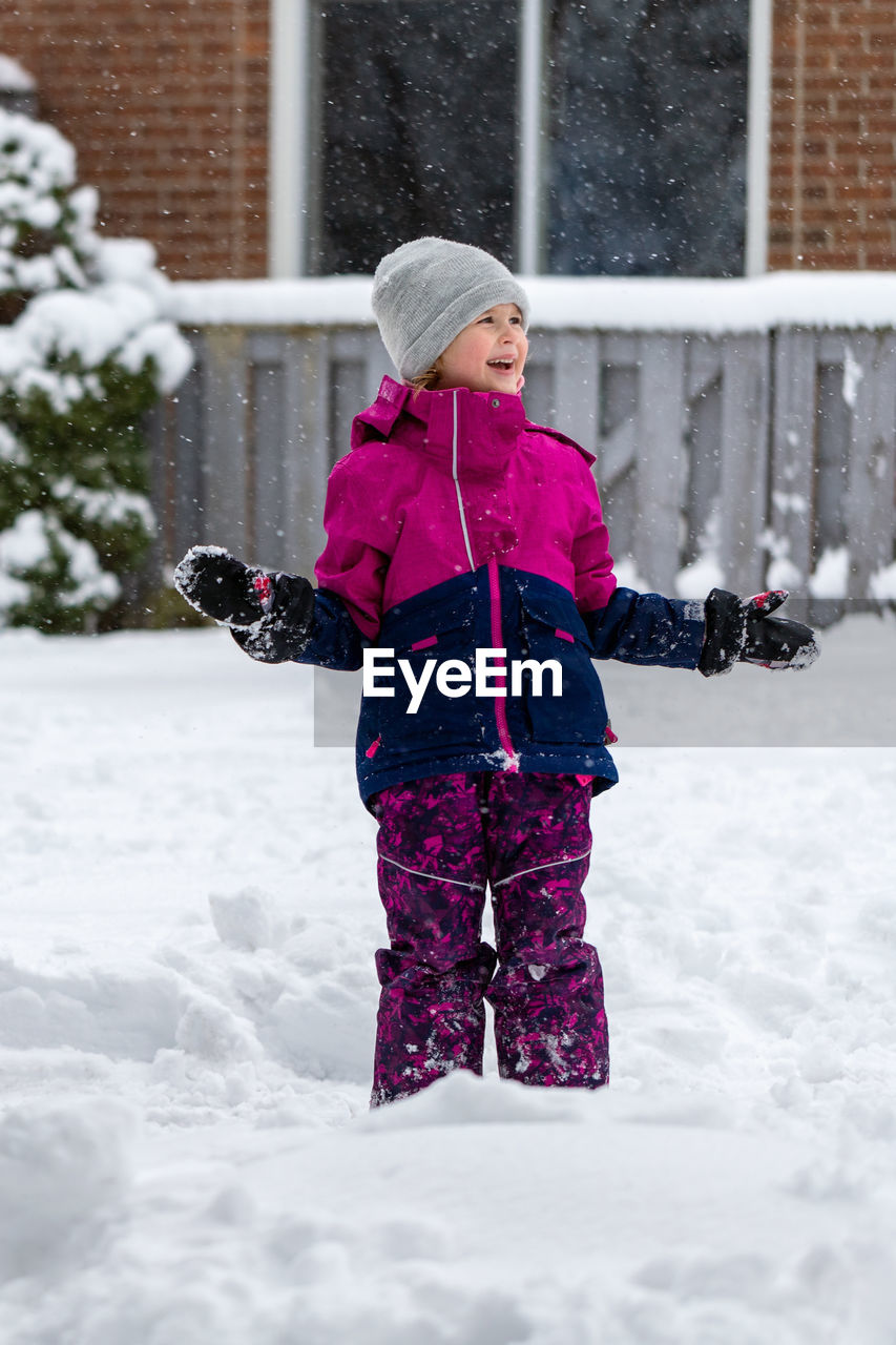 portrait of smiling boy standing on snow covered field