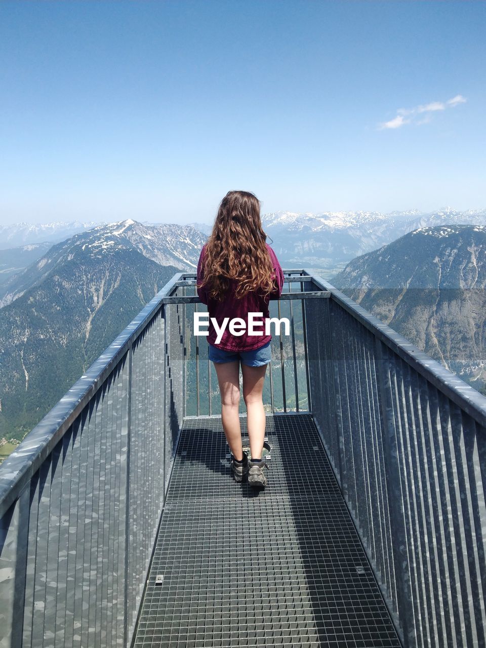 Rear view of woman standing by railing on observation point against sky