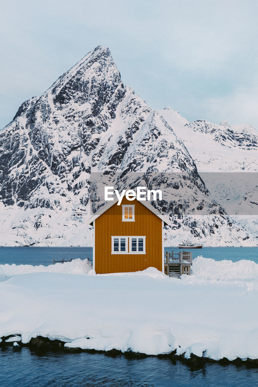 House on snowcapped mountain against sky