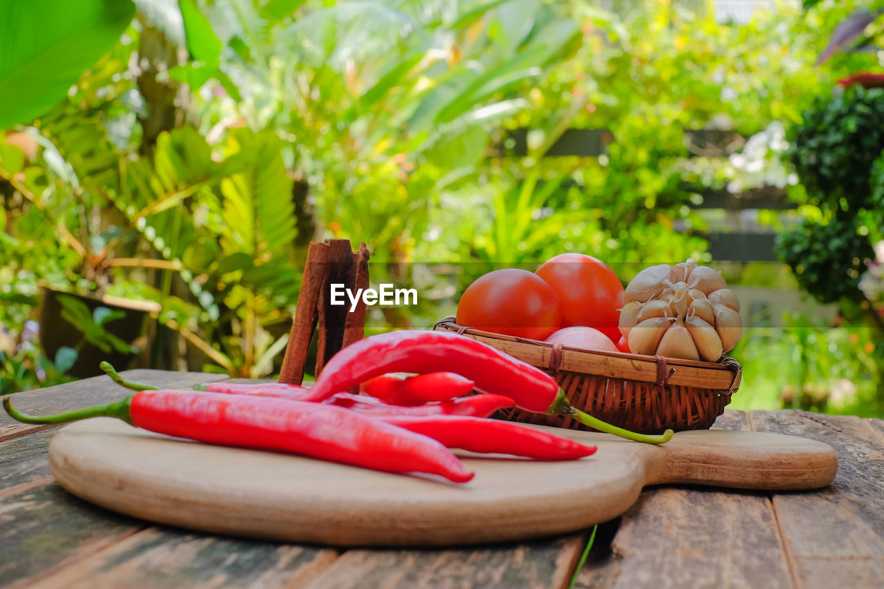 CLOSE-UP OF RED CHILI PEPPERS IN BASKET ON TABLE AGAINST WOODEN WALL