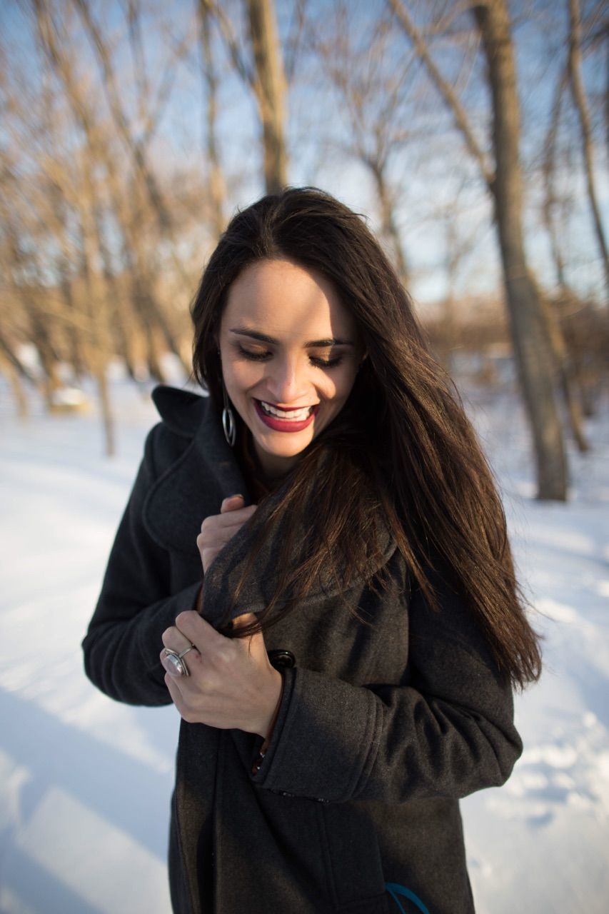 Smiling beautiful woman standing on snow covered field