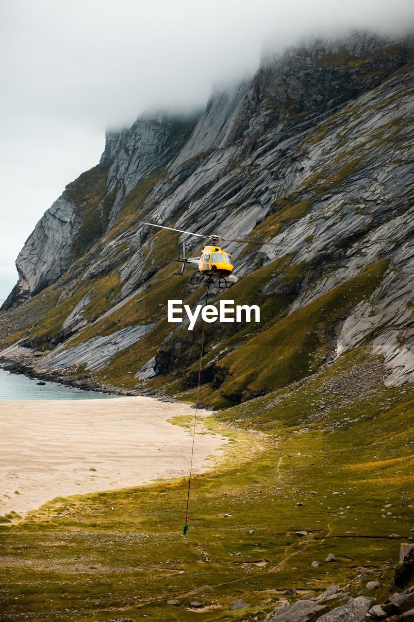 Scenic view of helicopter soaring by cloud-covered mountain. ideal for adventure projects.