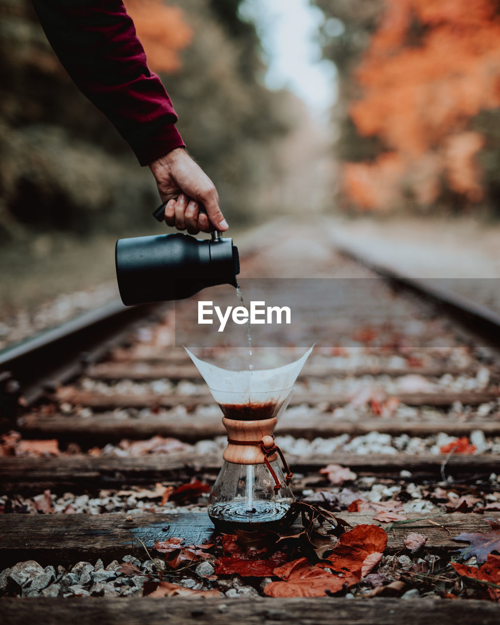 Cropped hand pouring water in coffee maker on railroad track