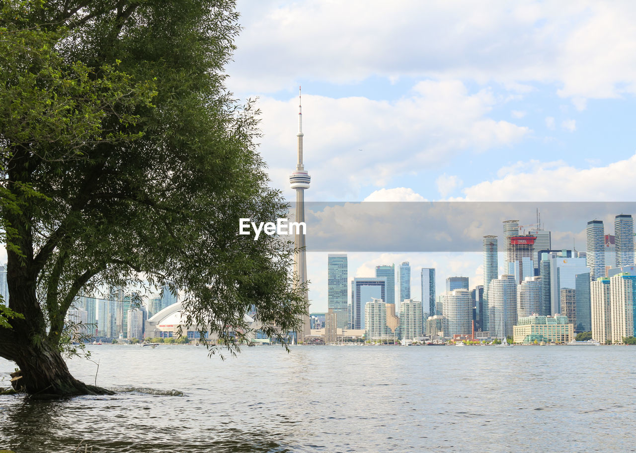 Modern cityscape by river against sky