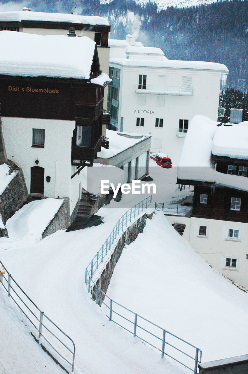 HIGH ANGLE VIEW OF SNOW COVERED HOUSES BY BUILDING