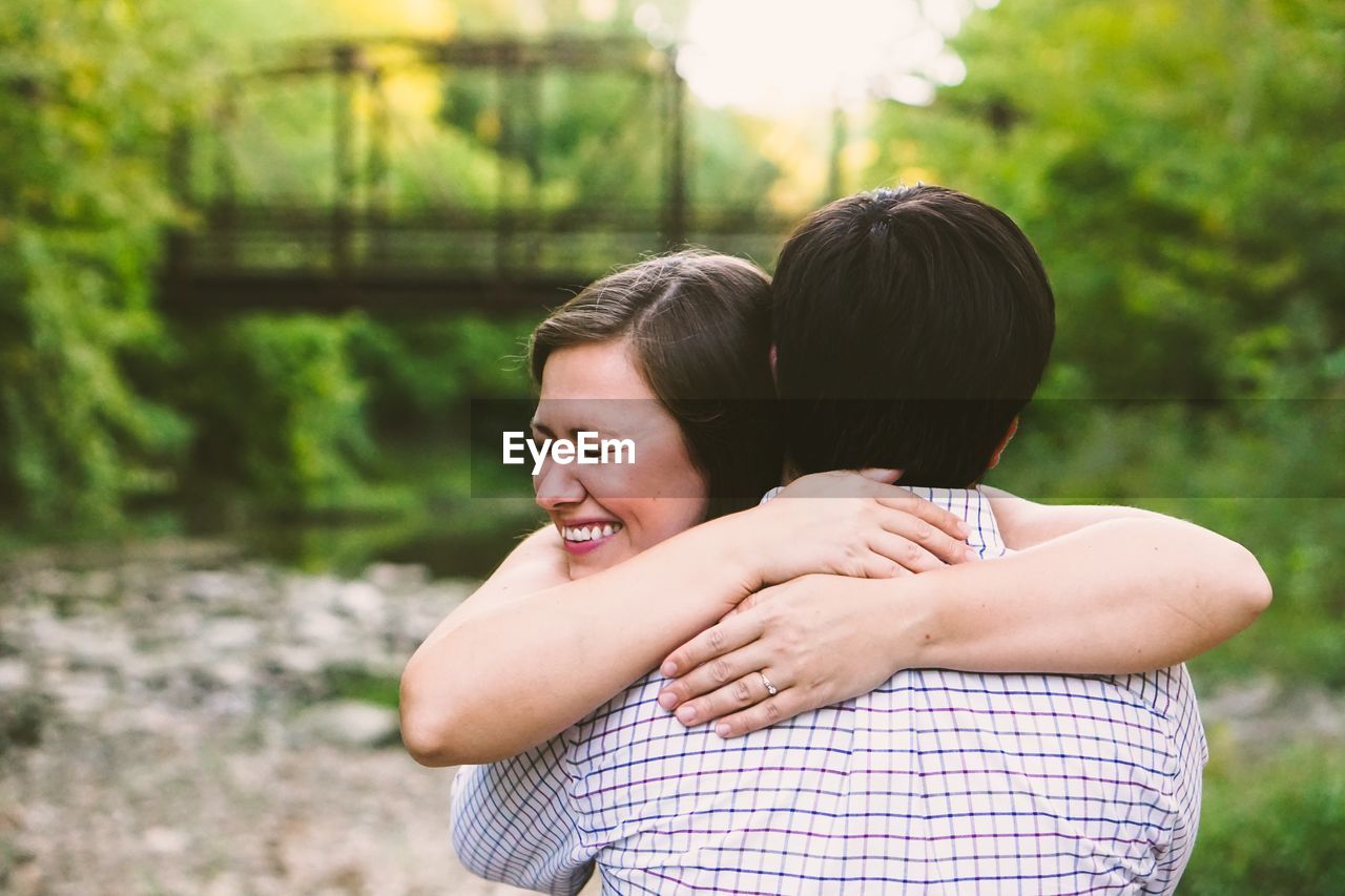 Romantic couple embracing while standing against trees in forest