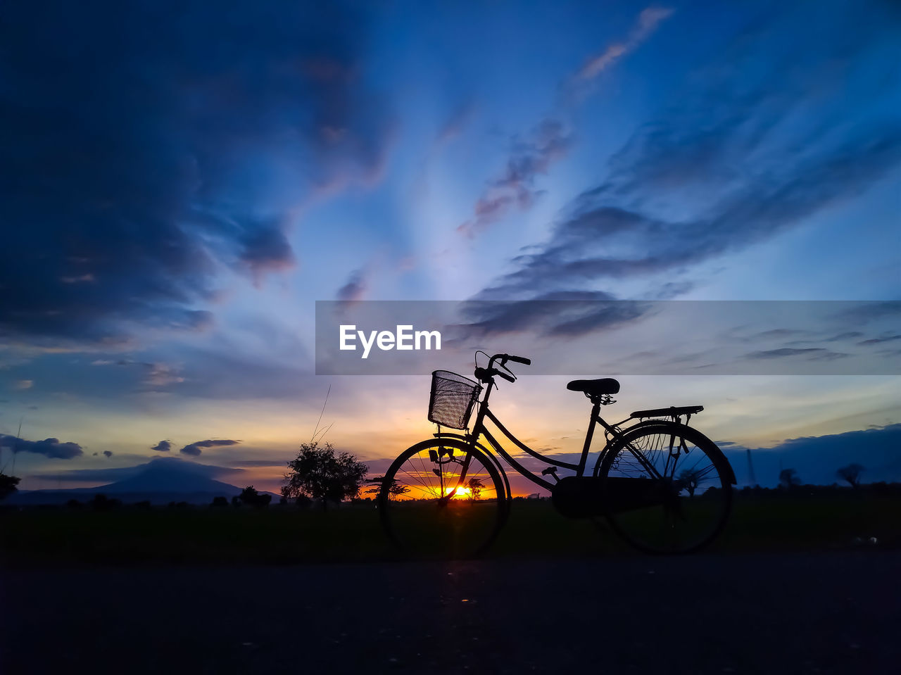 Silhouette bicycle on field against sky during sunset
