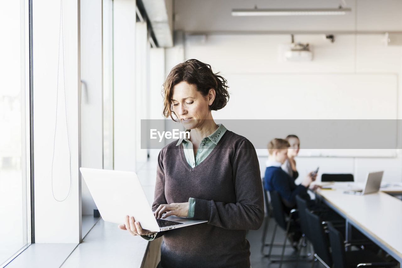 Professor using laptop in classroom