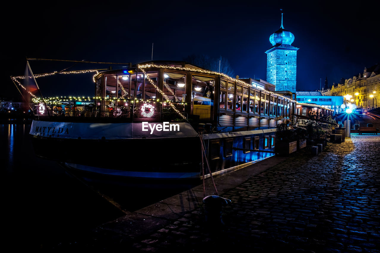 View of illuminated boats moored at river