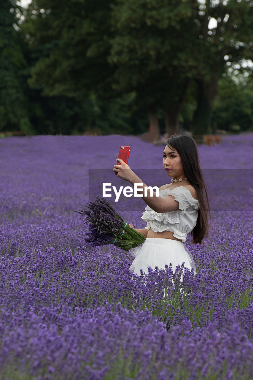 WOMAN STANDING ON PURPLE FLOWERING PLANT