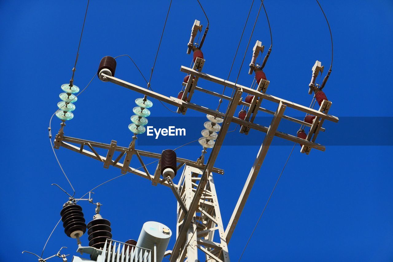 Low angle view of telephone pole against clear blue sky