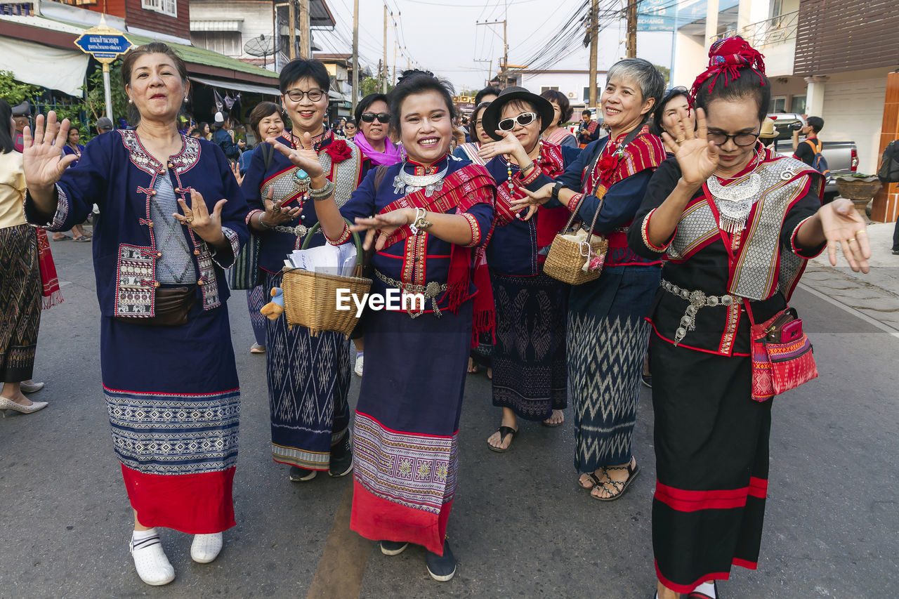 GROUP OF PEOPLE IN TRADITIONAL CLOTHING STANDING AGAINST CITY