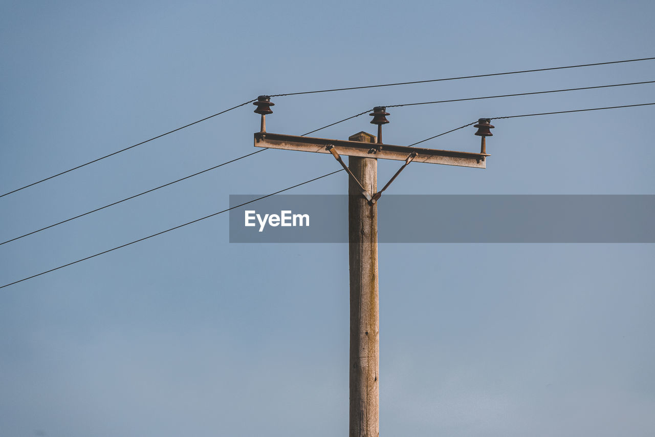 Low angle view of electricity pylon against clear sky