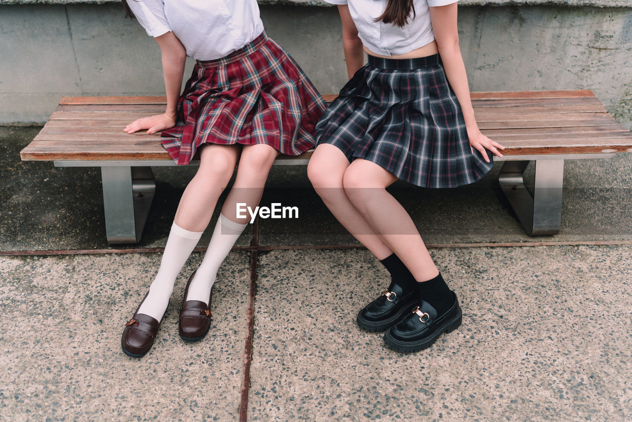 Low section of women sitting on bench