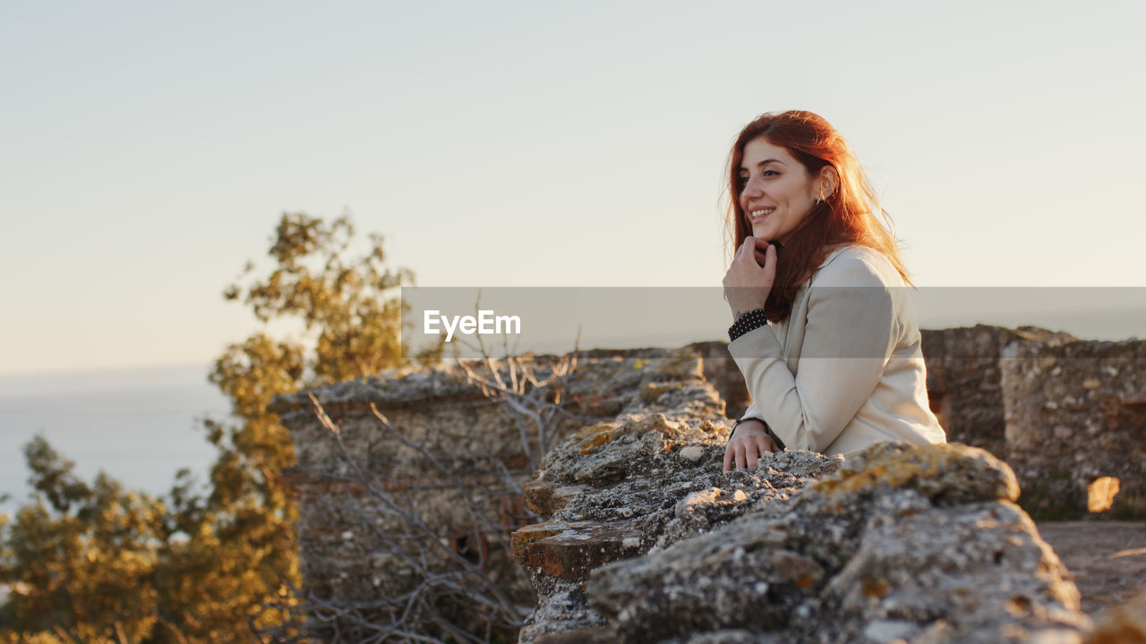 Beautiful girl with white dress explores an ancient italian castle at sunset