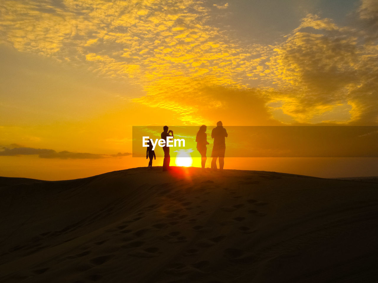 FRIENDS STANDING ON SAND DUNE IN DESERT