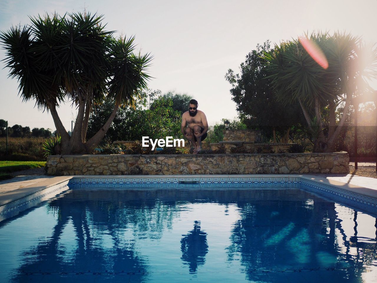 Full length of shirtless man jumping in swimming pool