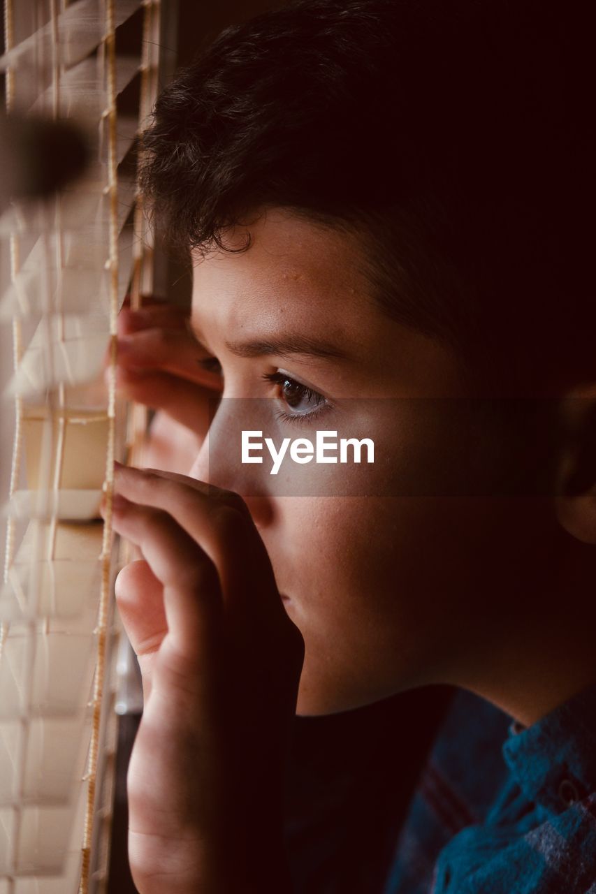 Close-up of boy looking through window