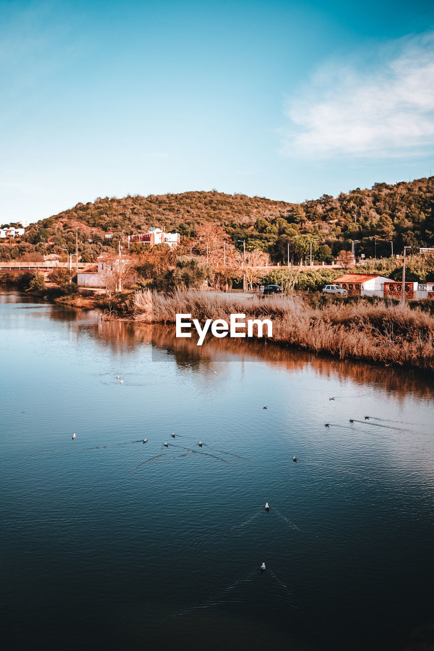 Scenic view of lake by buildings against sky