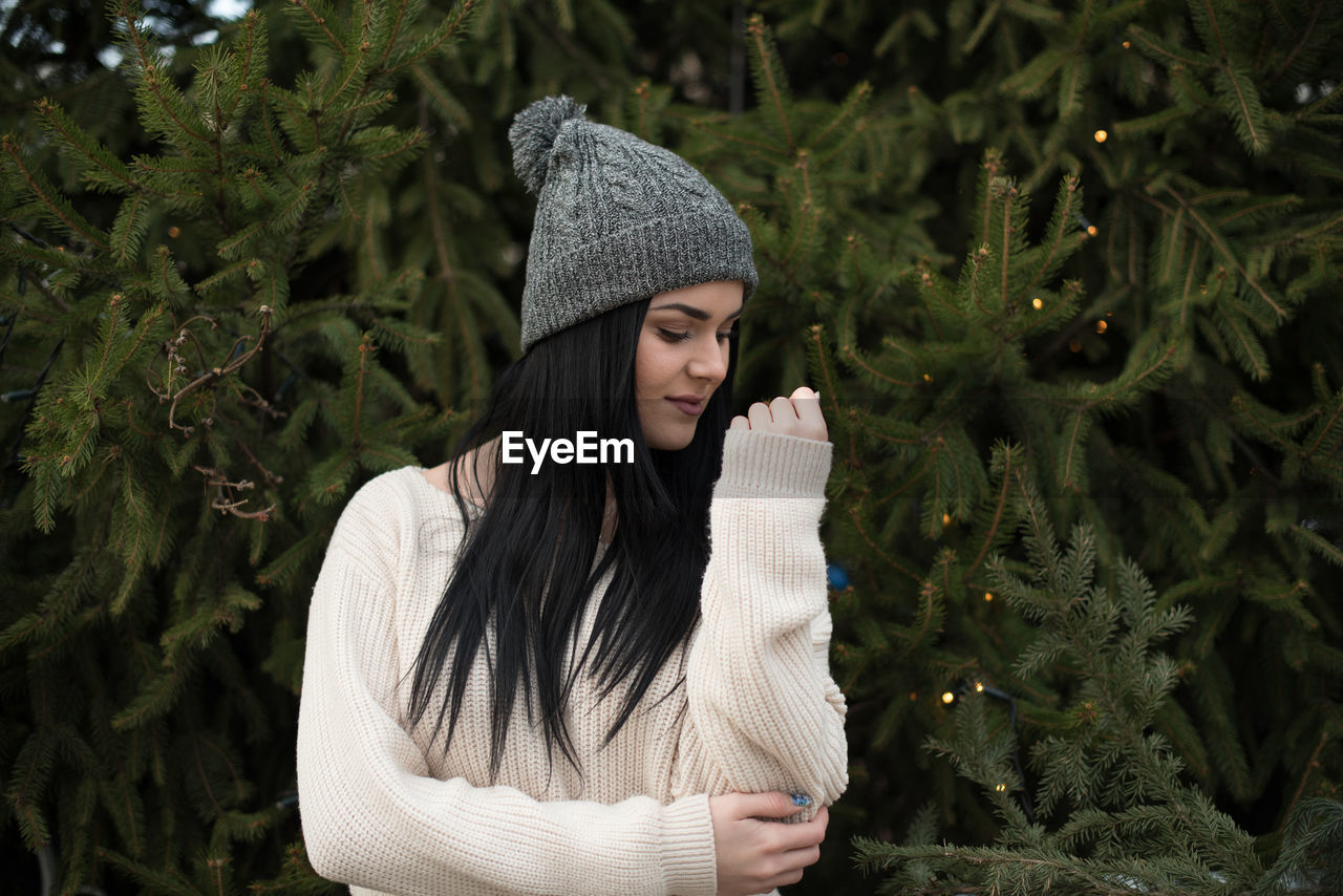 Young woman standing against christmas trees