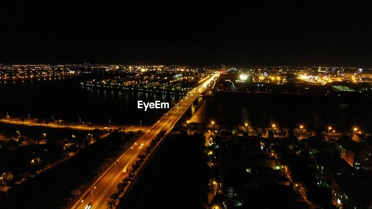 HIGH ANGLE VIEW OF ILLUMINATED CITY BUILDINGS AT NIGHT