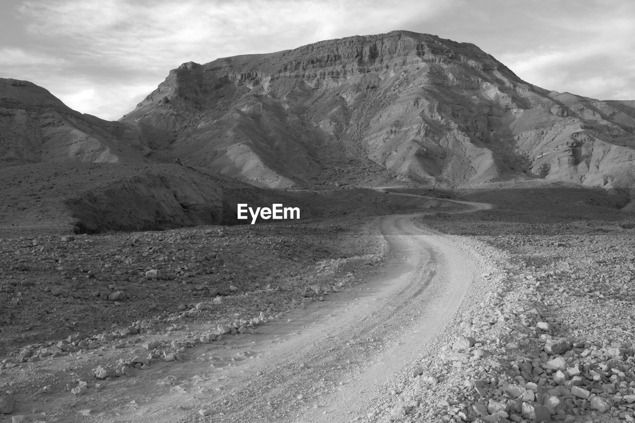 Scenic view of road by mountains against sky