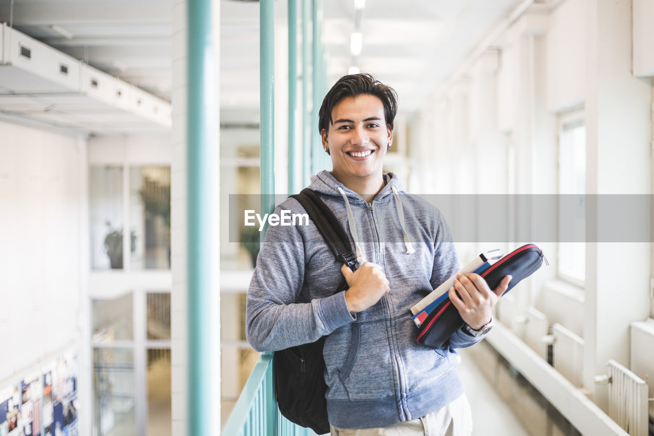 Portrait of confident young male student in corridor of university