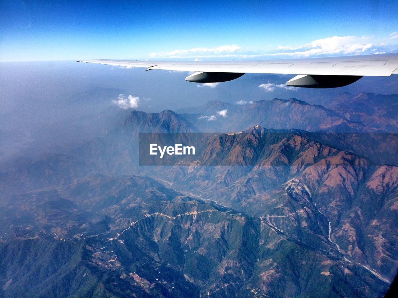 Cropped image of airplane wing over rocky mountains