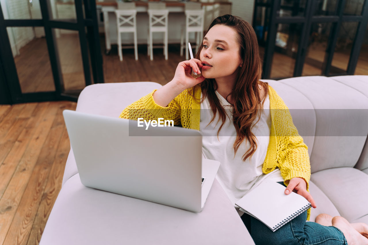 Young woman using phone while sitting on table