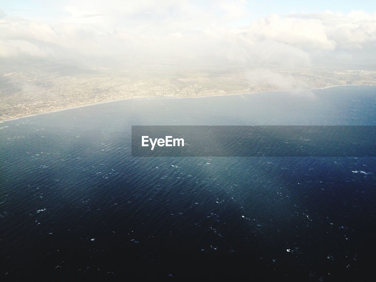 Aerial view of sea and land covering clouds