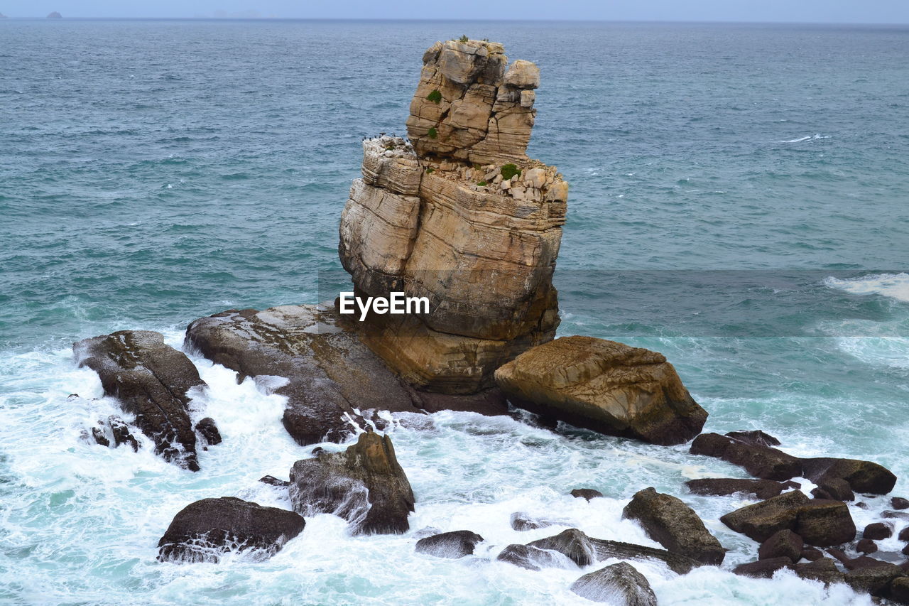 Rock formation on beach against sky