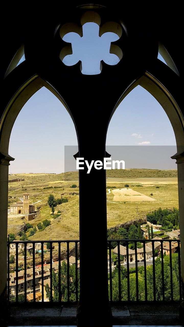 Scenic view of field against clear sky seen through arch