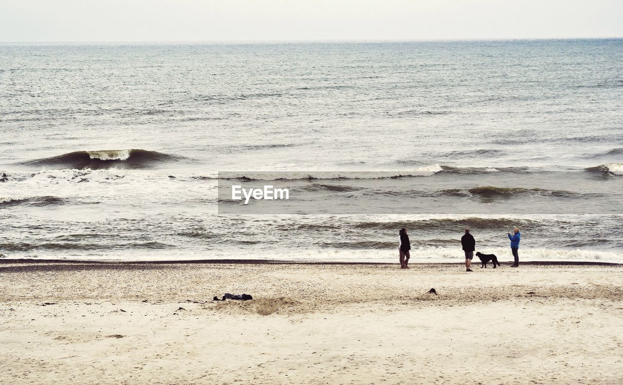 People relaxing at beach against sky