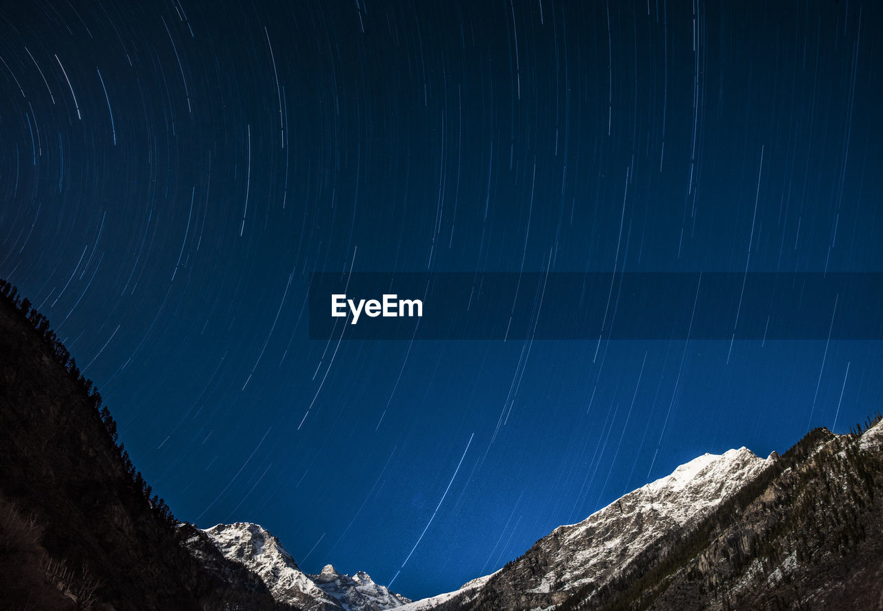 Star trail night photography with snow covered mountain peak