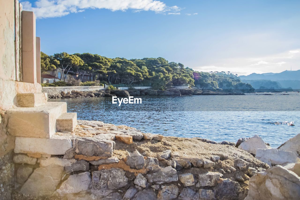 Scenic view of rocks by sea against sky