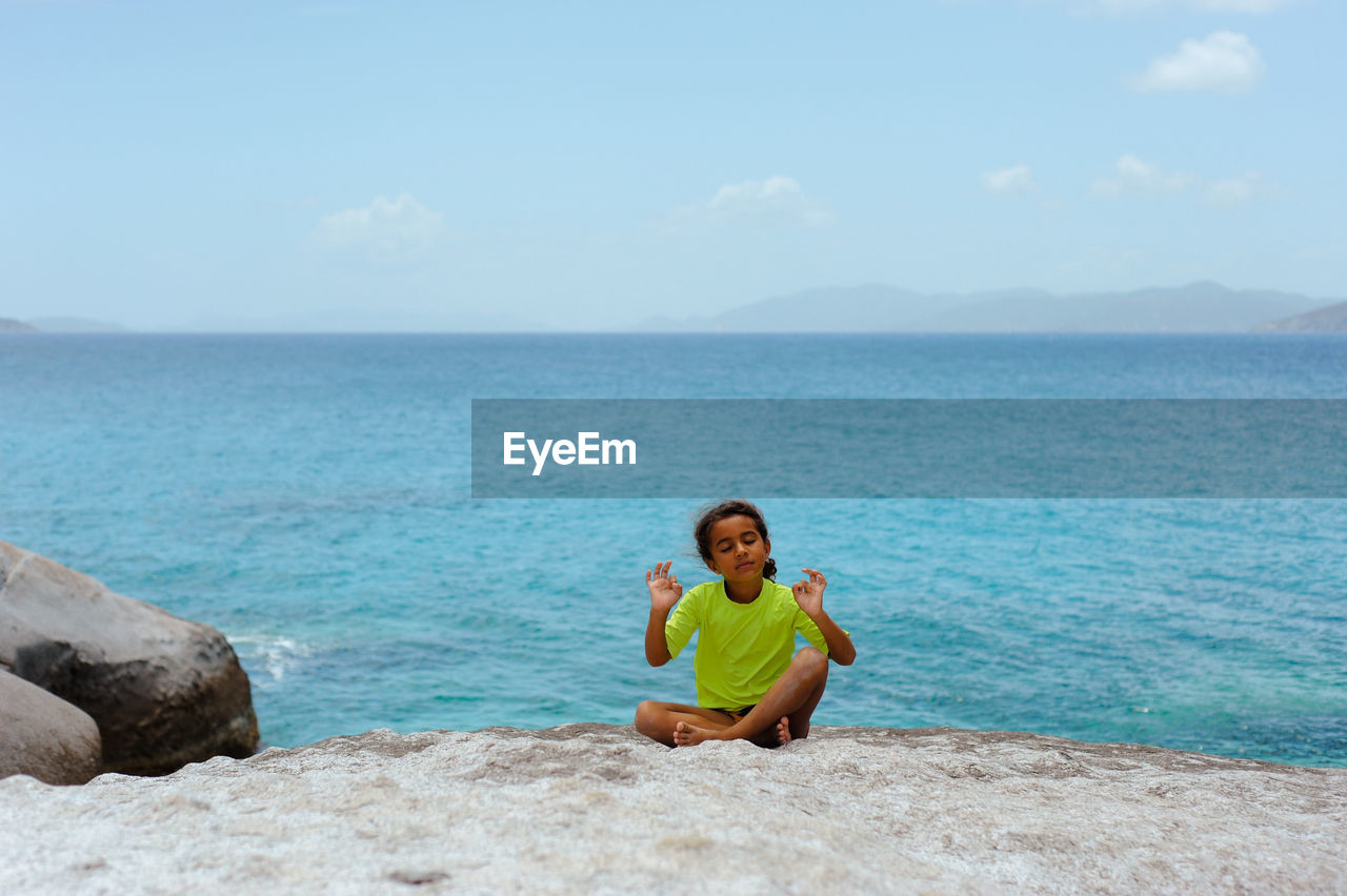 Girl with eyes closed sitting on beach