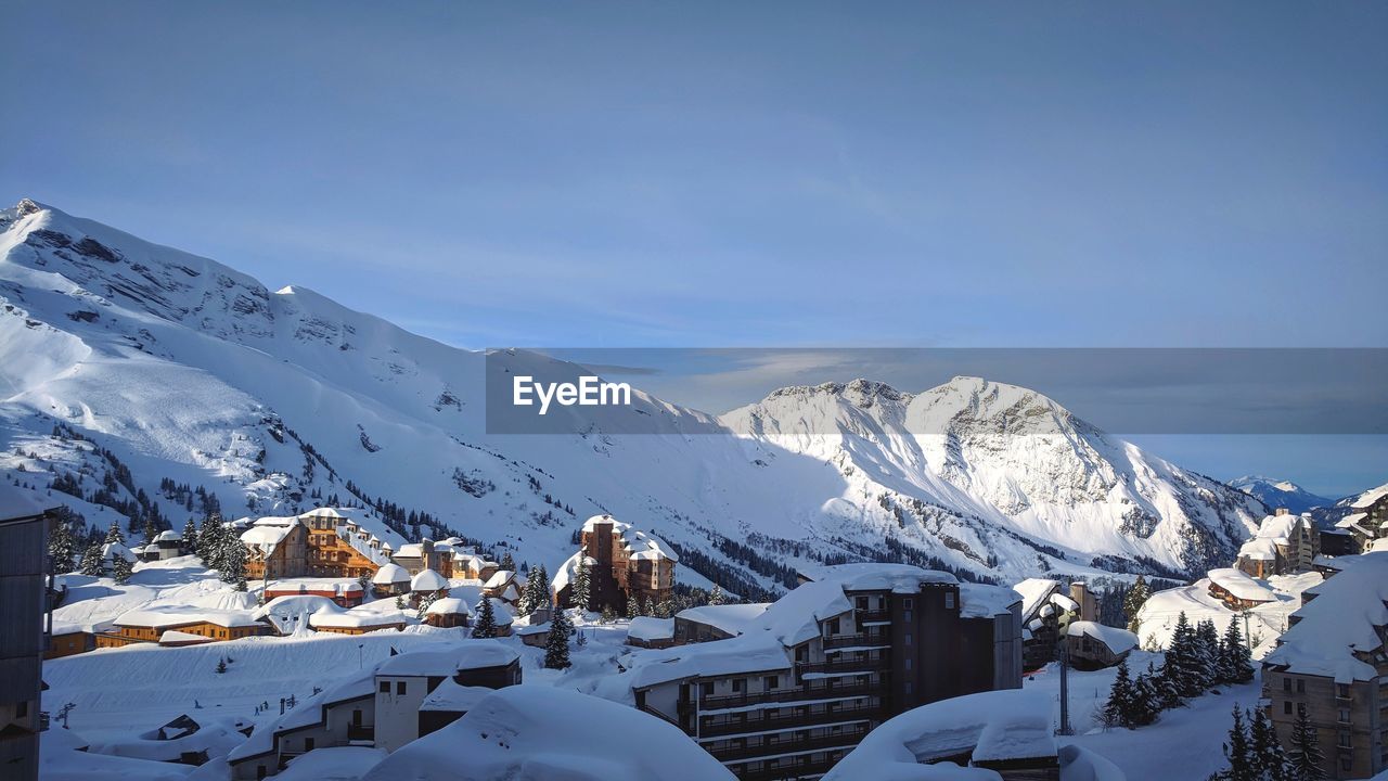 Houses on snowcapped mountain against a clear blue sky