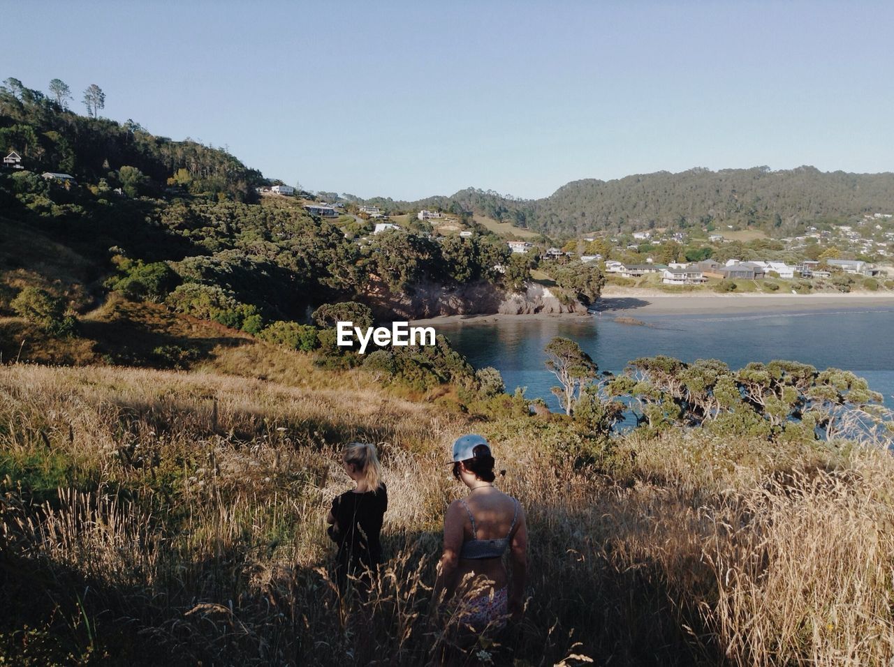 REAR VIEW OF PEOPLE OVERLOOKING CALM LAKE