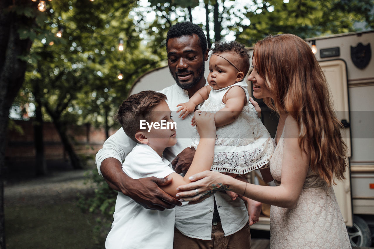 Cheerful family standing against van outdoors