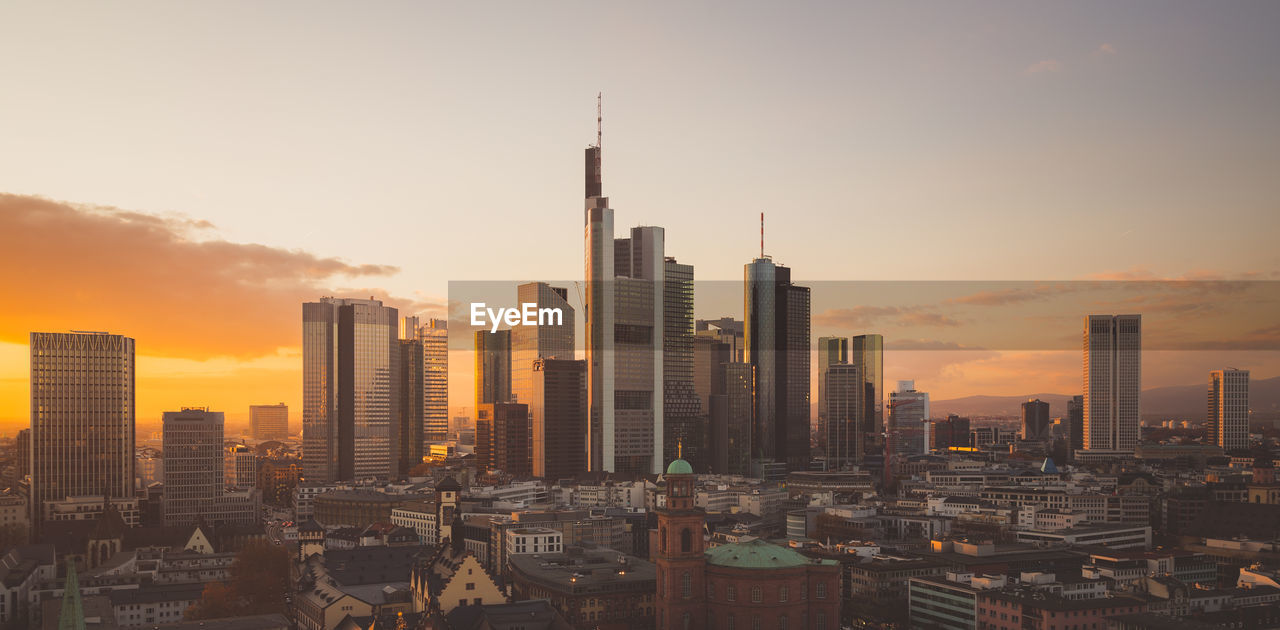 Buildings in city against sky during sunset