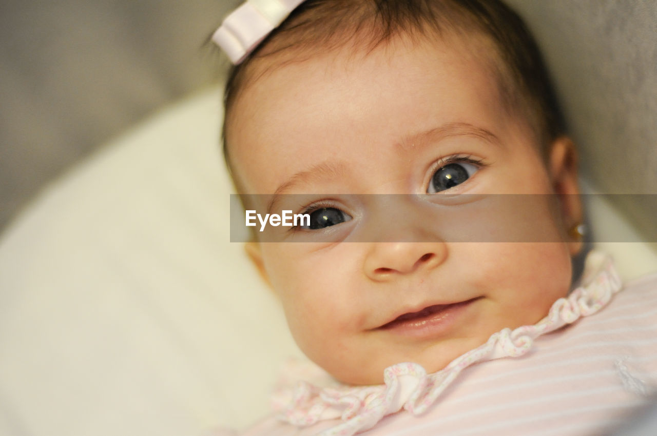 Close-up portrait of cute baby girl lying on bed