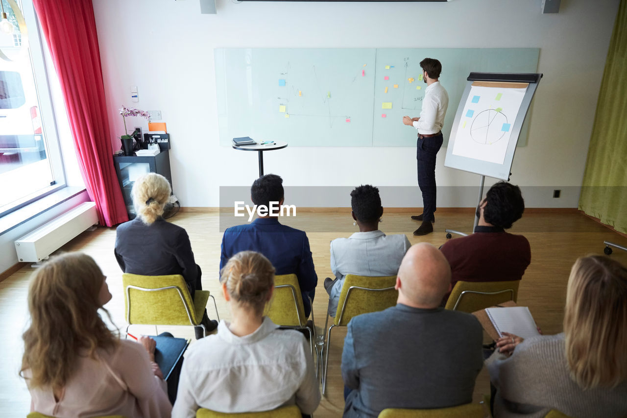 High angle view of businessman giving presentation to male and female coworkers in office workshop