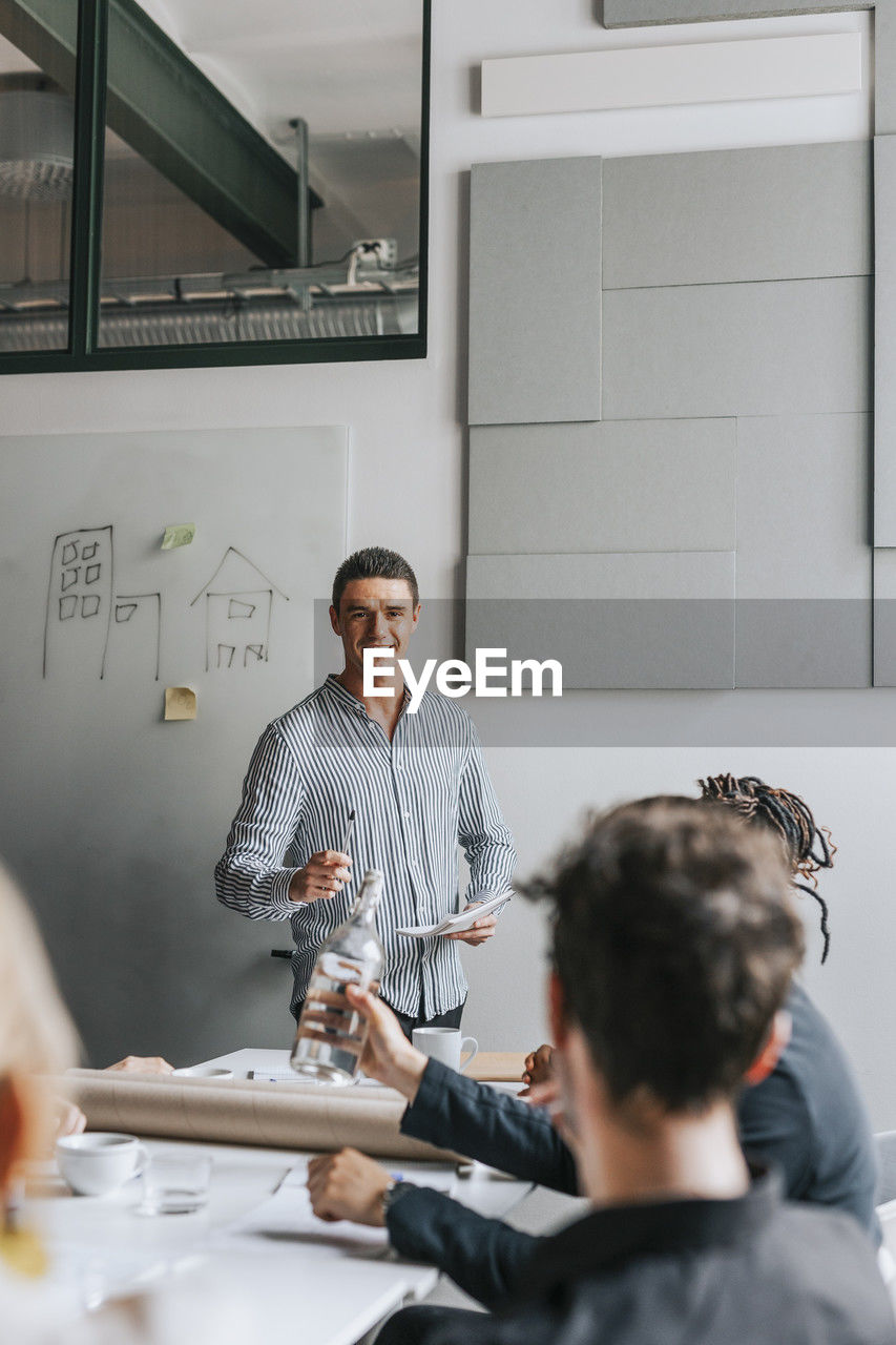 Smiling businessman explaining colleagues during meeting at office