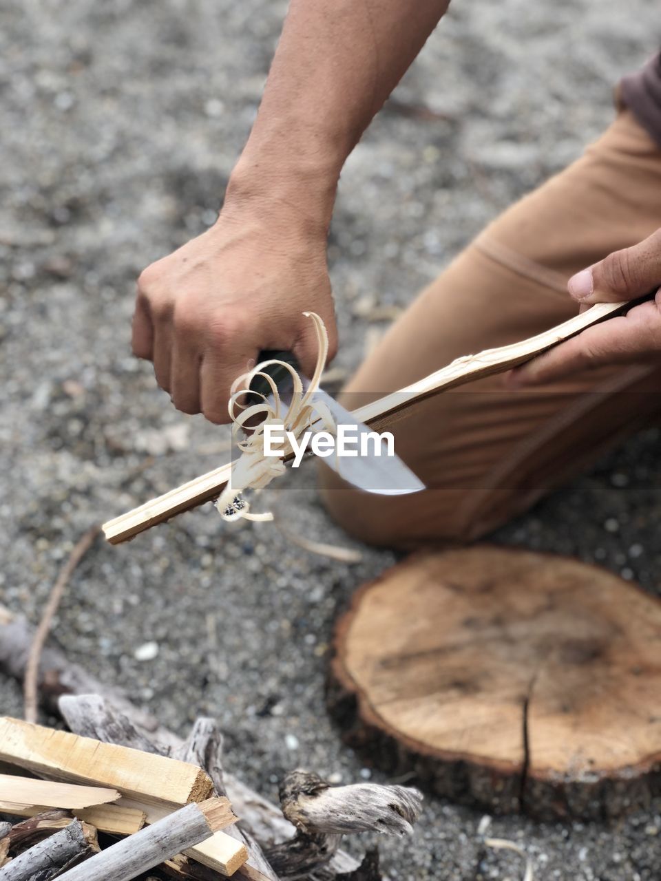 High angle view of man scraping wooden stick at campsite