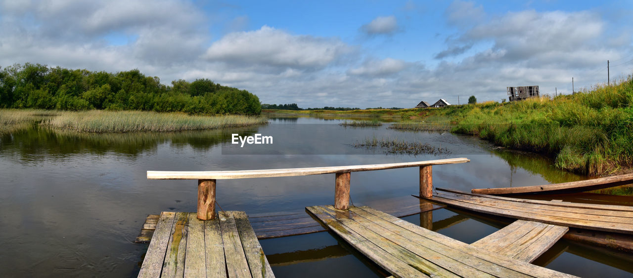 Wooden jetty on lake against sky
