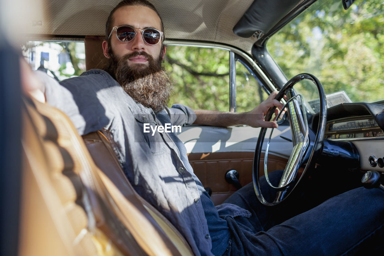 Looking across the front seat of bearded man in a vintage car